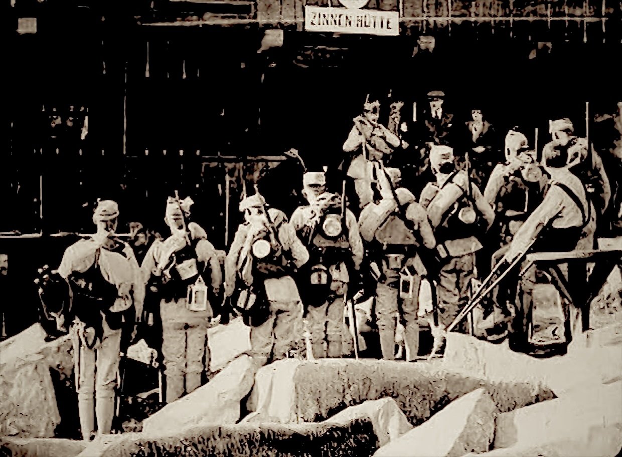 Film still: mountain guides with packs and ice axes gather outside the Zinnen Hütte