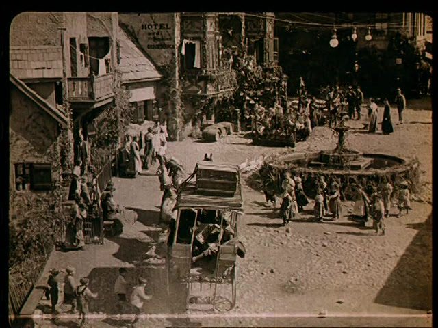 Film still: an alpine village with a stagecoach