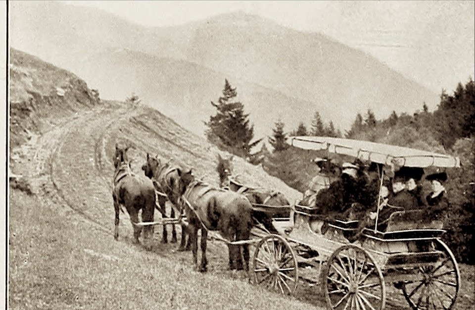 A four-horse stage coach full of passengers on a mountain road